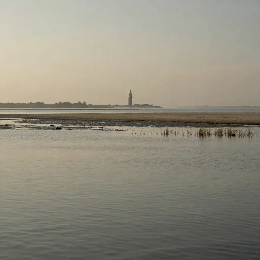 Laguna veneta al mattino con campanile lontano, acqua ferma e barene nella nebbia